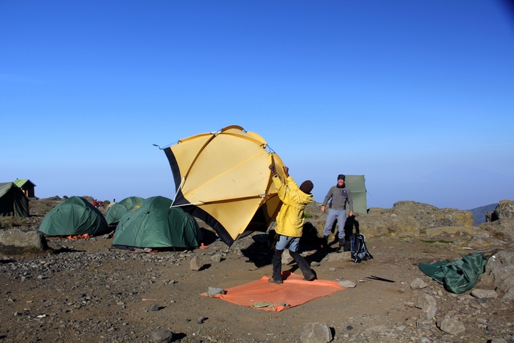       A person setting up a tent in a mountainous camping area.
  
