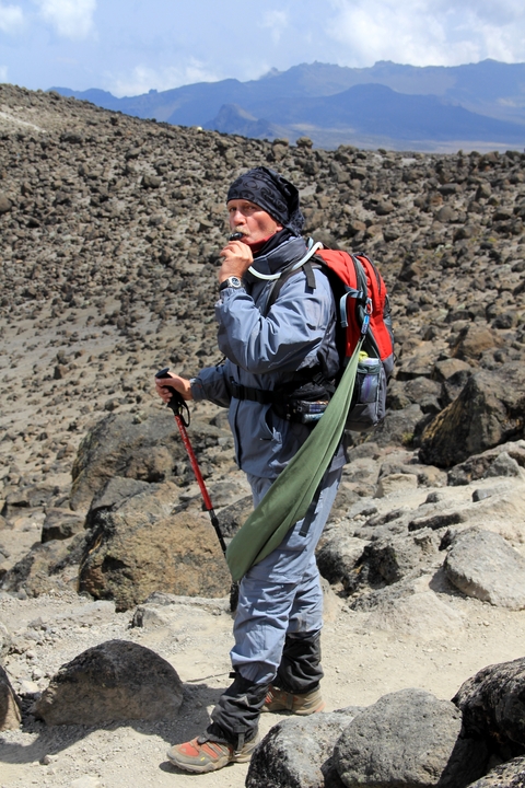       A hiker resting on a rocky path in mountain gear.
  