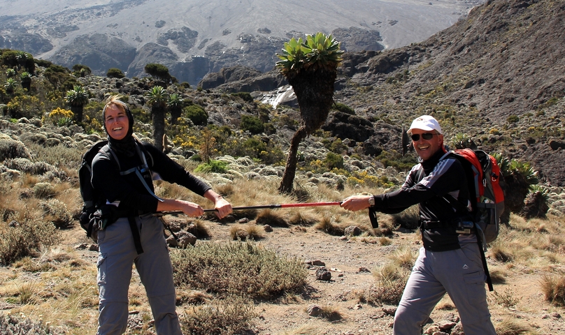       Two hikers playfully holding a trekking pole between them.
  
