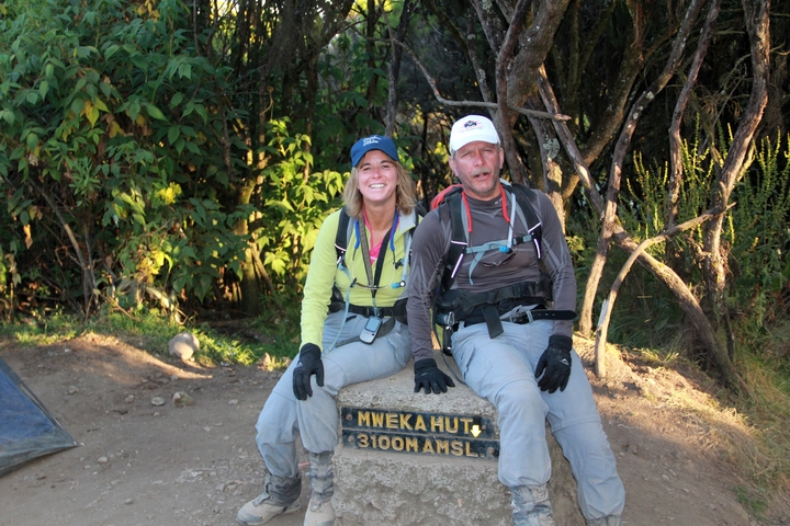       Two hikers sitting by a sign at Mweka Hut
  