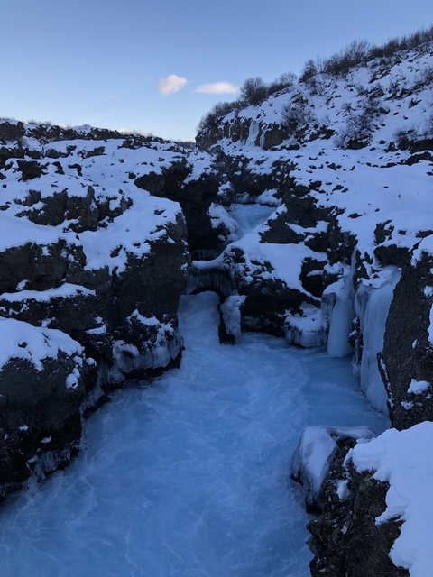       A frozen river surrounded by snow-covered cliffs
  