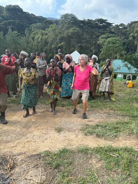       A group of people posing outdoors, surrounded by greenery.
  