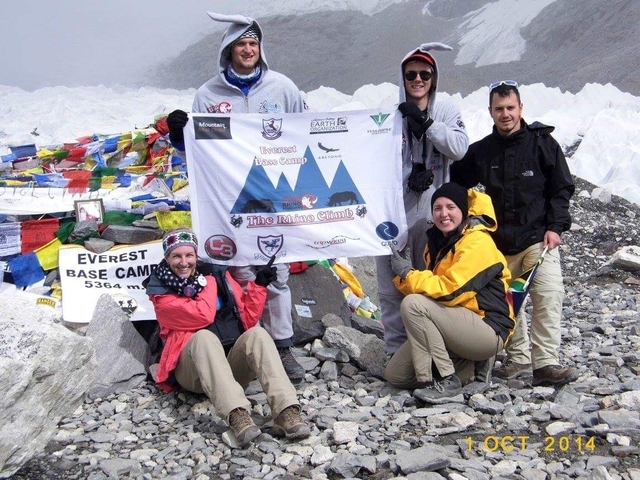 Group of people at Everest Base Camp with a sign.
