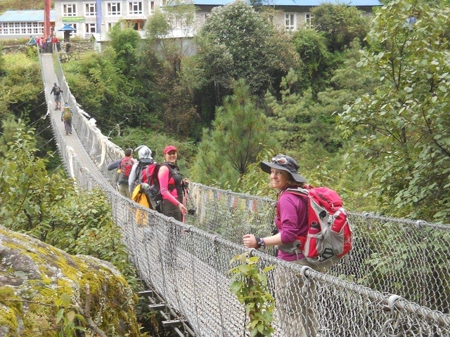 Hikers crossing a suspension bridge.