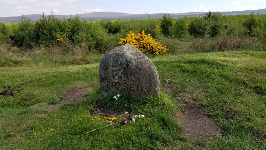 Memorial stone with 'CLAN FRASER', surrounded by greenery.