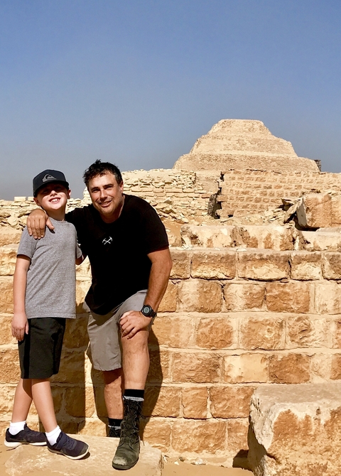       Father and child posing with ancient ruins in the background.
  