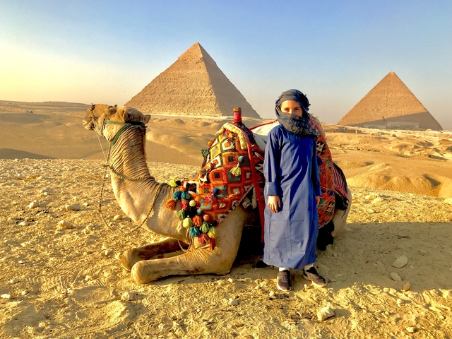       Person with a camel in front of the Pyramids.
  