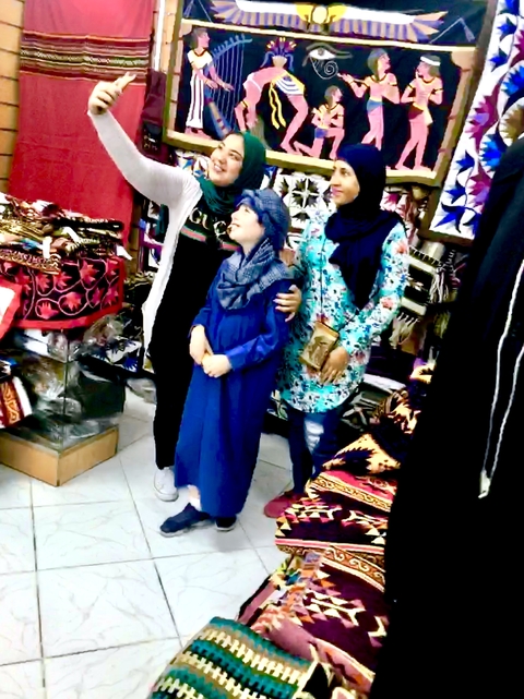       Family dressed in traditional clothes in a market setting.
  