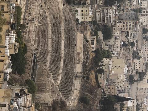 View of an ancient amphitheater and city buildings.
