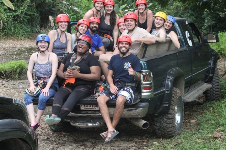 Group of people wearing helmets sitting in a truck bed.