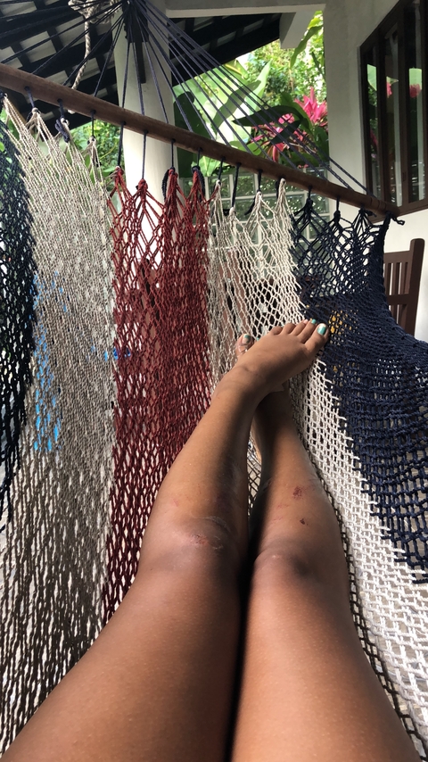Close-up of feet relaxing on a hammock.