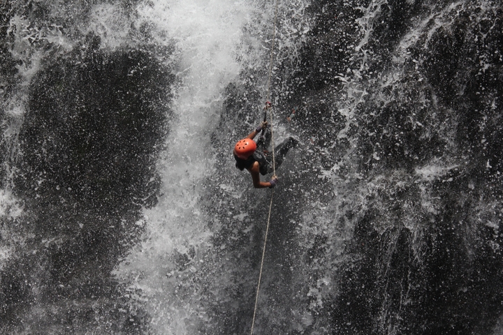 Person rappelling down a waterfall.