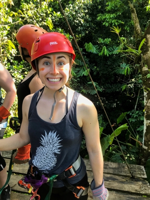 Close-up of a smiling woman in the jungle wearing a helmet.