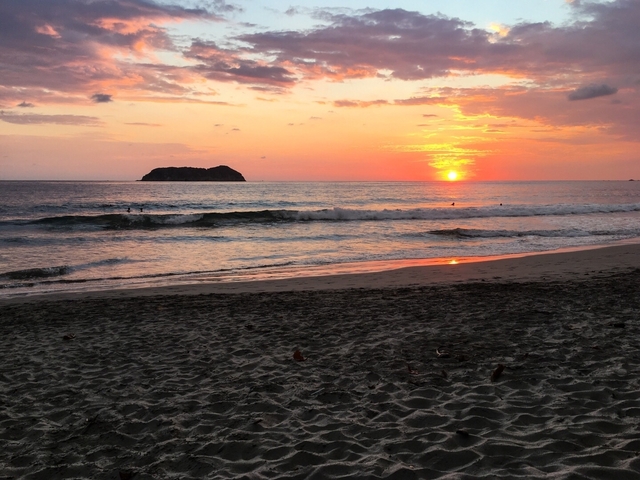       Sunset over the ocean with an island in the distance.
  