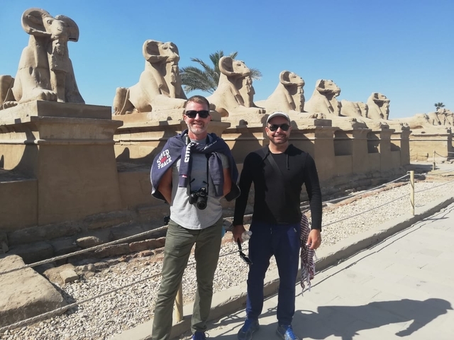 Two men standing in front of ancient Egyptian statues.