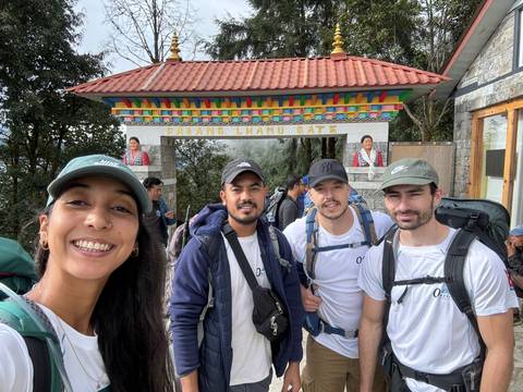       Group of people posing in front of a gate with colorful architecture.
  