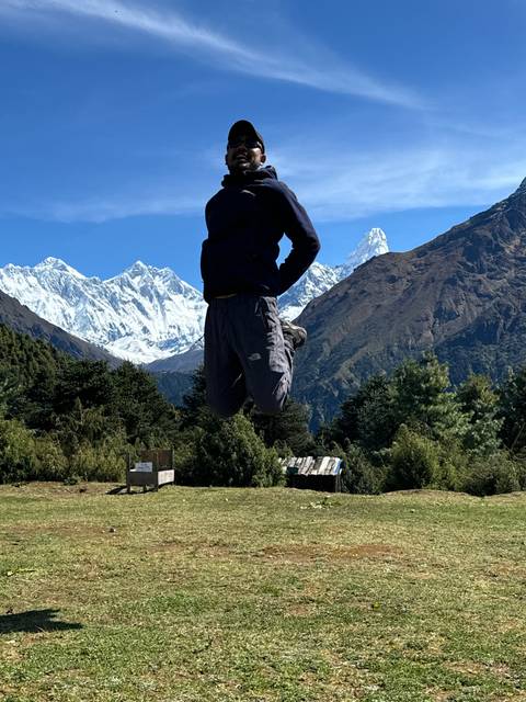       Person performing a jump with snow peaks in the background.
  