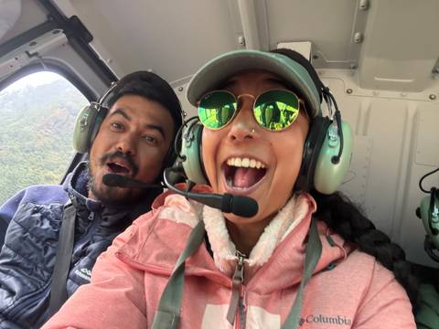       Two people smiling inside a helicopter.
  