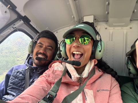       Two people smiling during a helicopter ride.
  