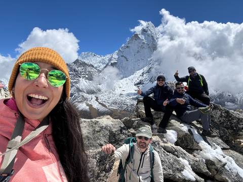      Group of people posing with mountains and clouds behind them.
  