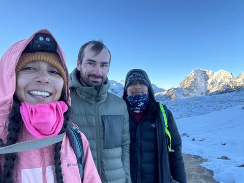 Three people wearing winter gear on a snowy mountaintop.