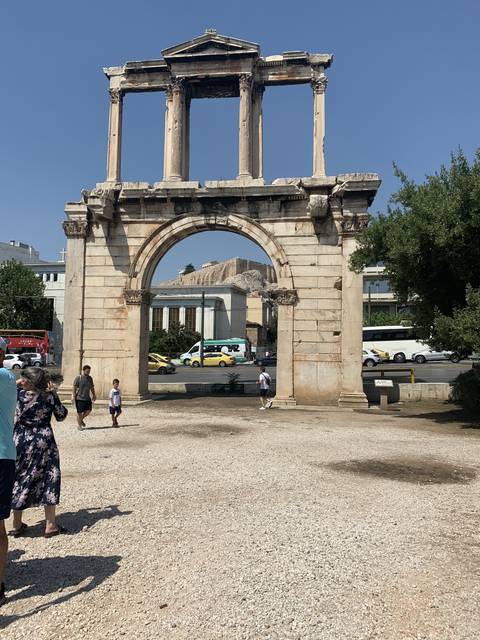       Ruins of an ancient gate with modern city view in the background.
  