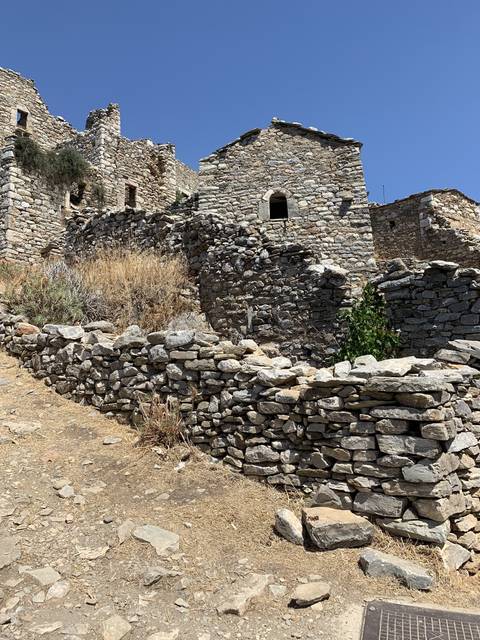       Ancient stone buildings on a dry hillside.
  