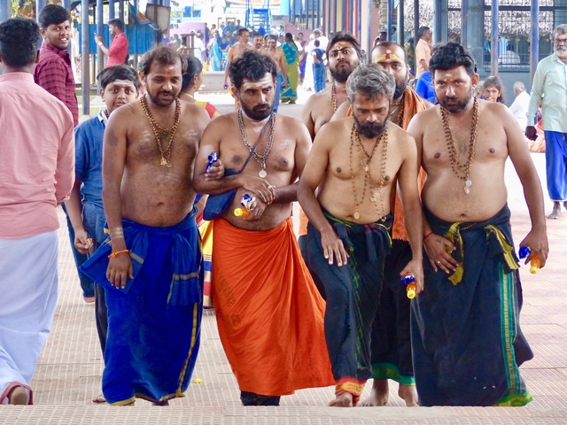 Men in traditional attire walking in temple courtyard.