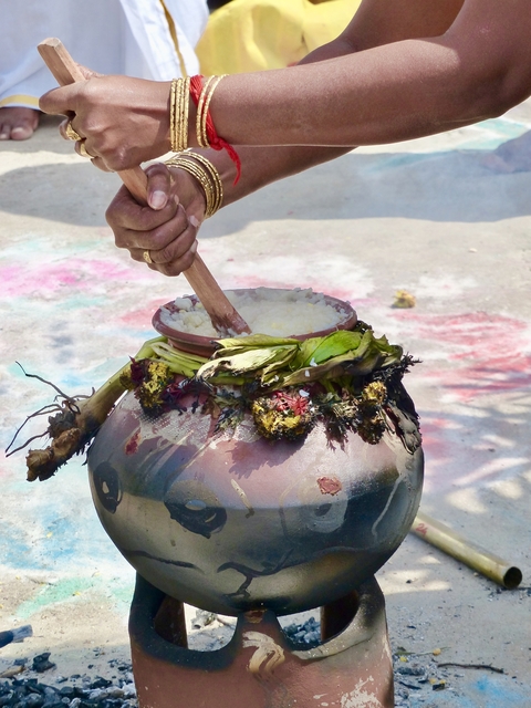       Traditional pot being stirred with rice inside.
  