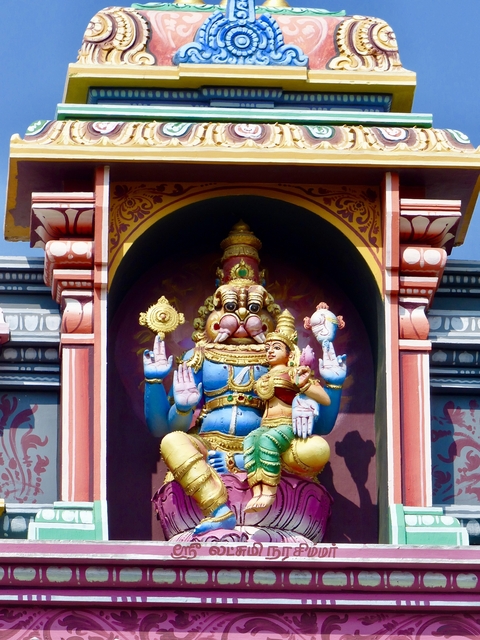 Colorful temple sculpture of deity with figures around.