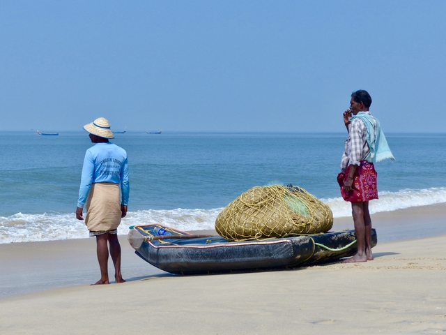 Fishermen preparing to cast net by the seashore.