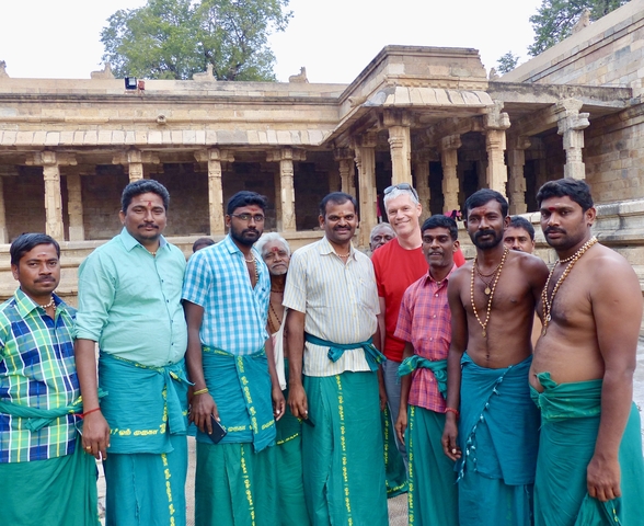       Men posing in traditional attire inside a temple.
  