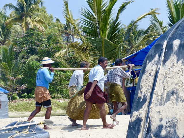       Fishermen carrying netting by the seaside.
  