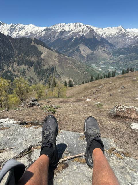 Feet of a person dangling over a valley with mountains.