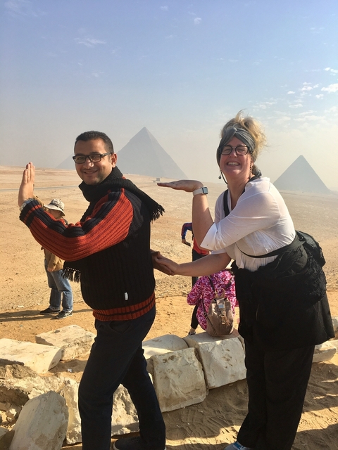       Two people posing with the pyramids in the background.
  