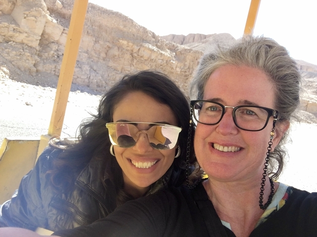      Two people smiling for a selfie with desert landscape in the background.
  