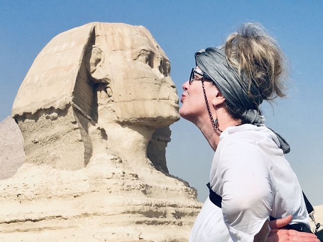       Person playfully posing for a photo in front of the Sphinx.
  