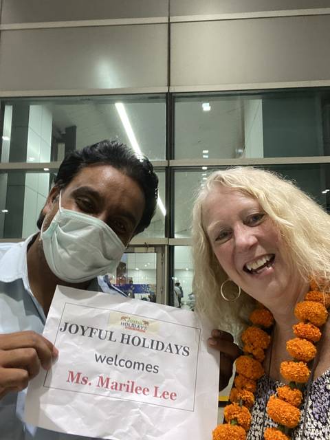       Two people meeting at an airport with a welcome sign.
  
