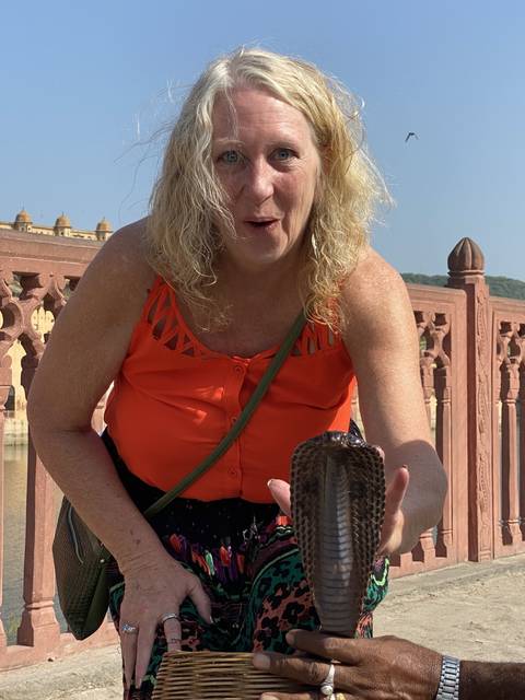       Woman holding a snake near a historical site.
  