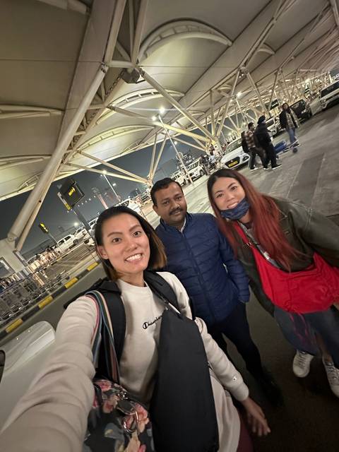       Group of people taking a selfie in an airport environment.
  
