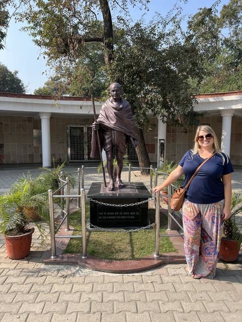 Woman standing beside a statue of Gandhi.