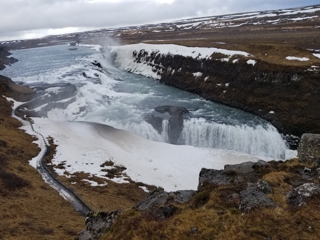 Frozen waterfall surrounded by icy landscape, Iceland.