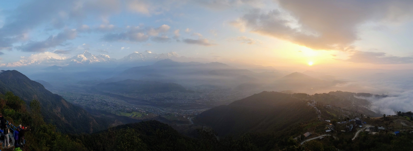 Wide panorama of a valley with mountains at sunset.