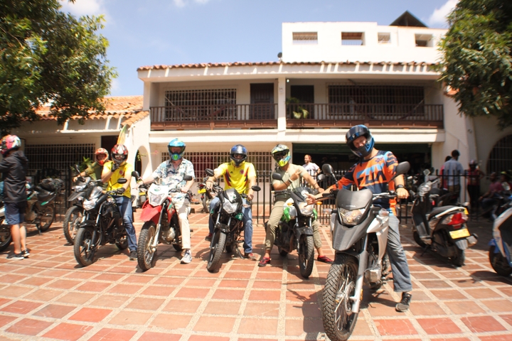       Group of motorcyclists posing with their bikes in front of a building.
  