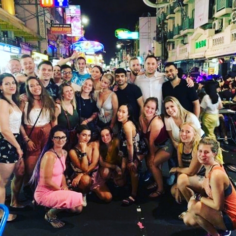 Group of friends posing together in a lively street at night.