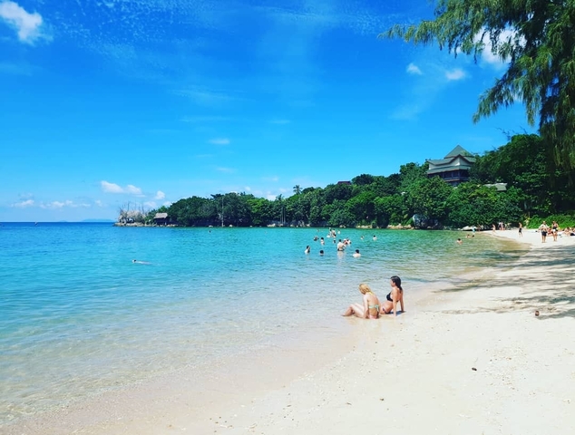Tropical beach with clear water and people swimming.