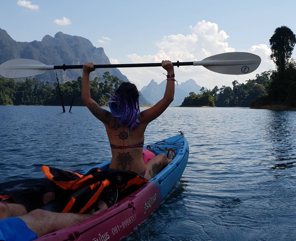 A person kayaking on a lake with mountains in the background.