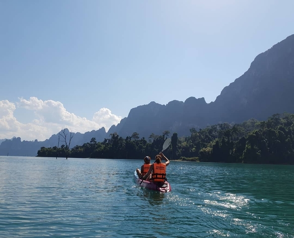 Two people kayaking on a lake with mountains visible.