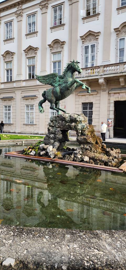       Statue of a horse in front of a historical building.
  