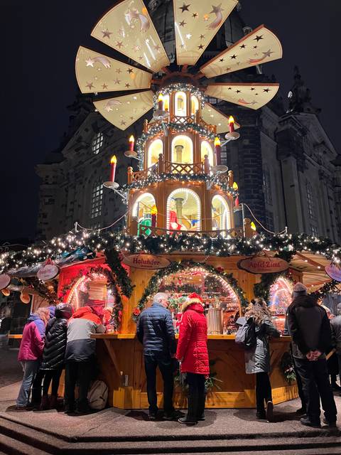       Christmas market stall with people viewing decorations at night
  